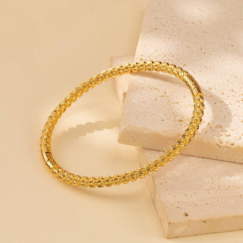 Stainless steel bracelet with 18K gold-plated spherical twisted wire texture, elegant modern art.